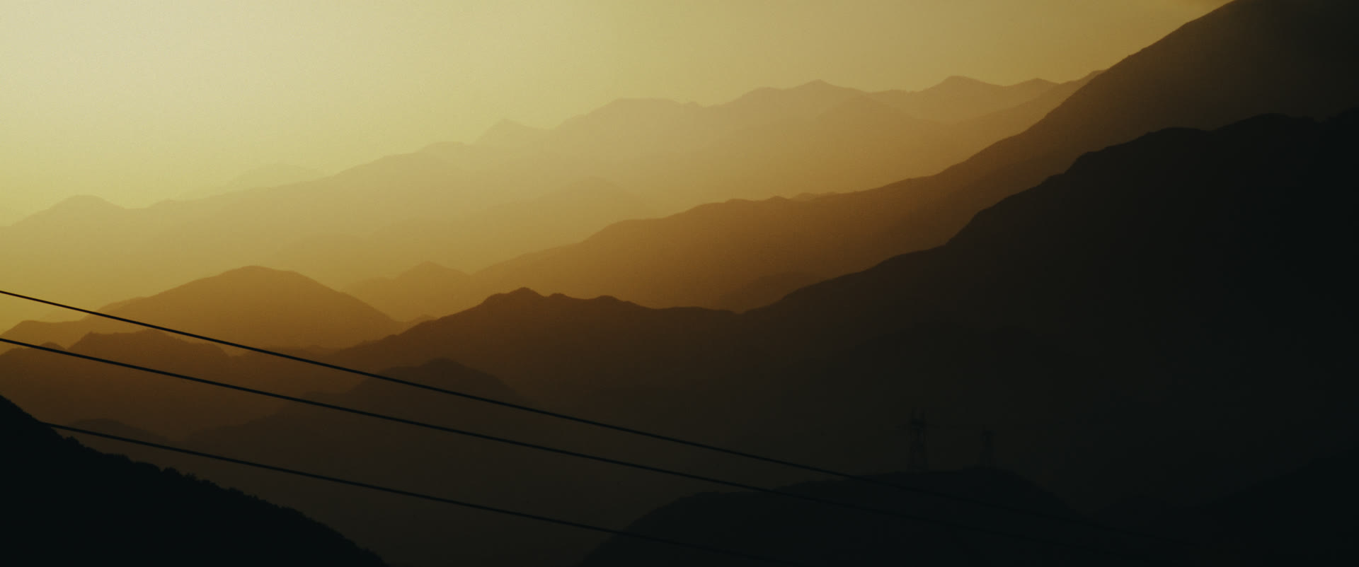Layered mountain ridgelines in golden haze at sunset — still from Memories