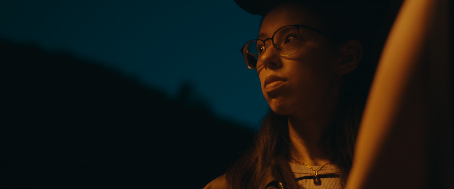 A woman gazes into the night in warm light — still from Memories