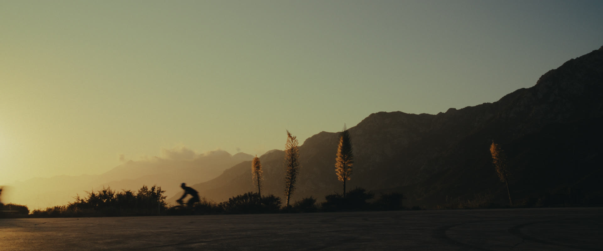 A cyclist crests a mountain road at sunset — still from Memories