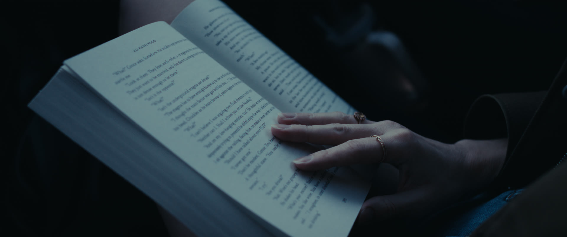 A hand resting on an open paperback — still from Memories