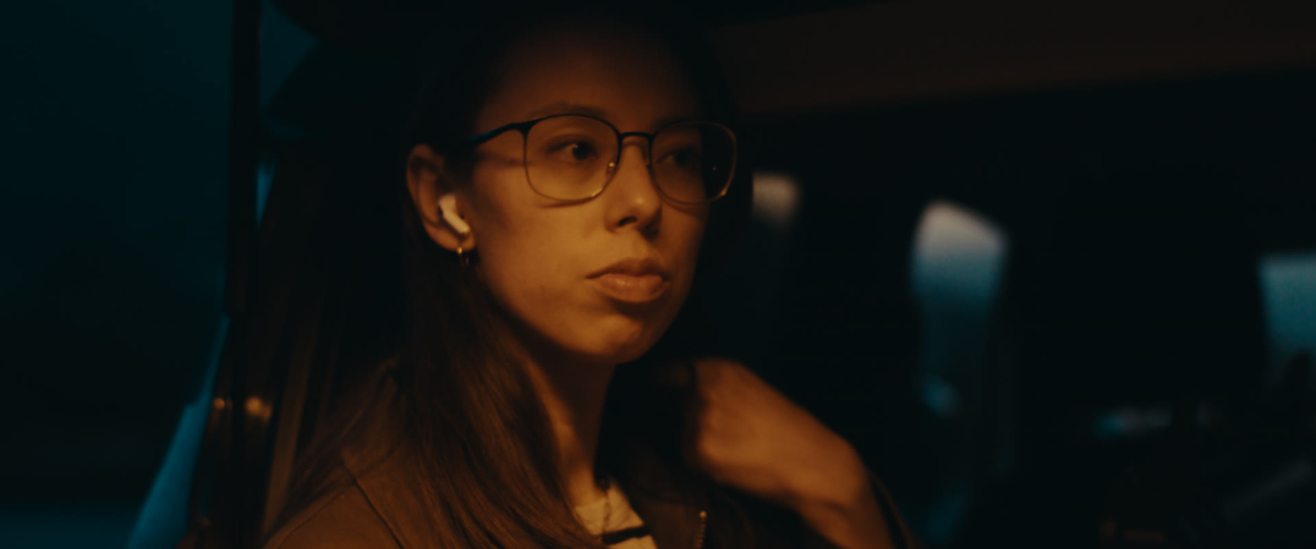 A woman with an earbud in warm lamplight at night — still from Memories