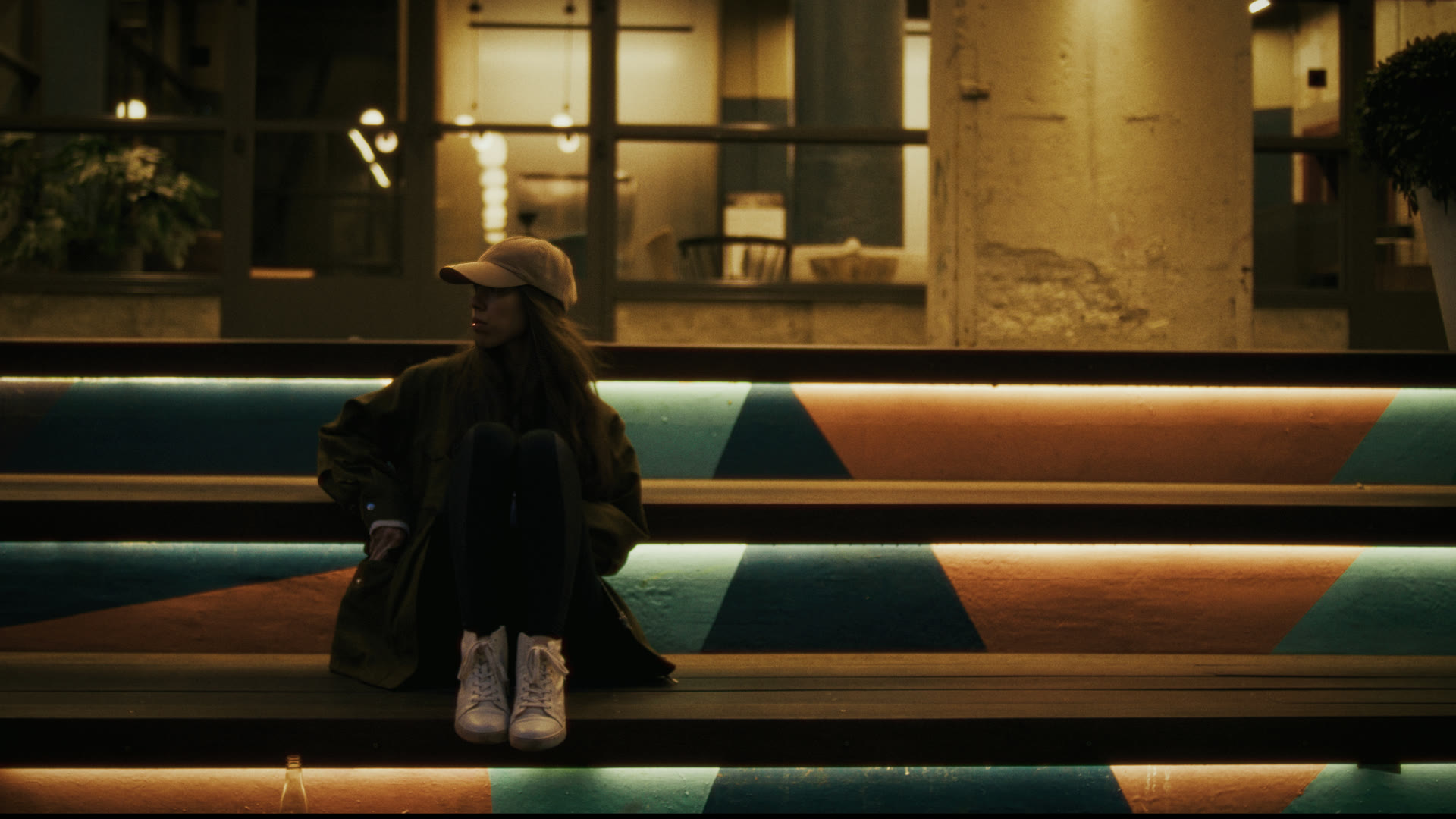 A woman sits alone on colorful painted steps at night — still from The Row